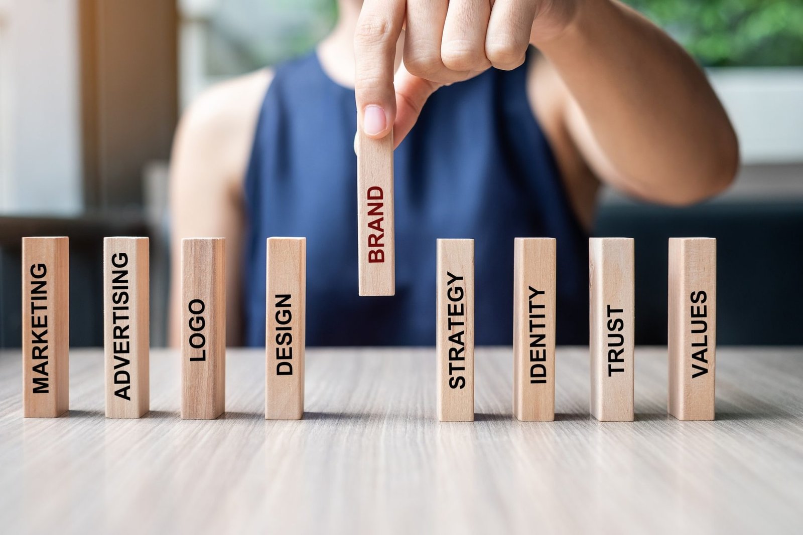 Projects businesswoman hand placing wooden dominoes with text e1645157376444