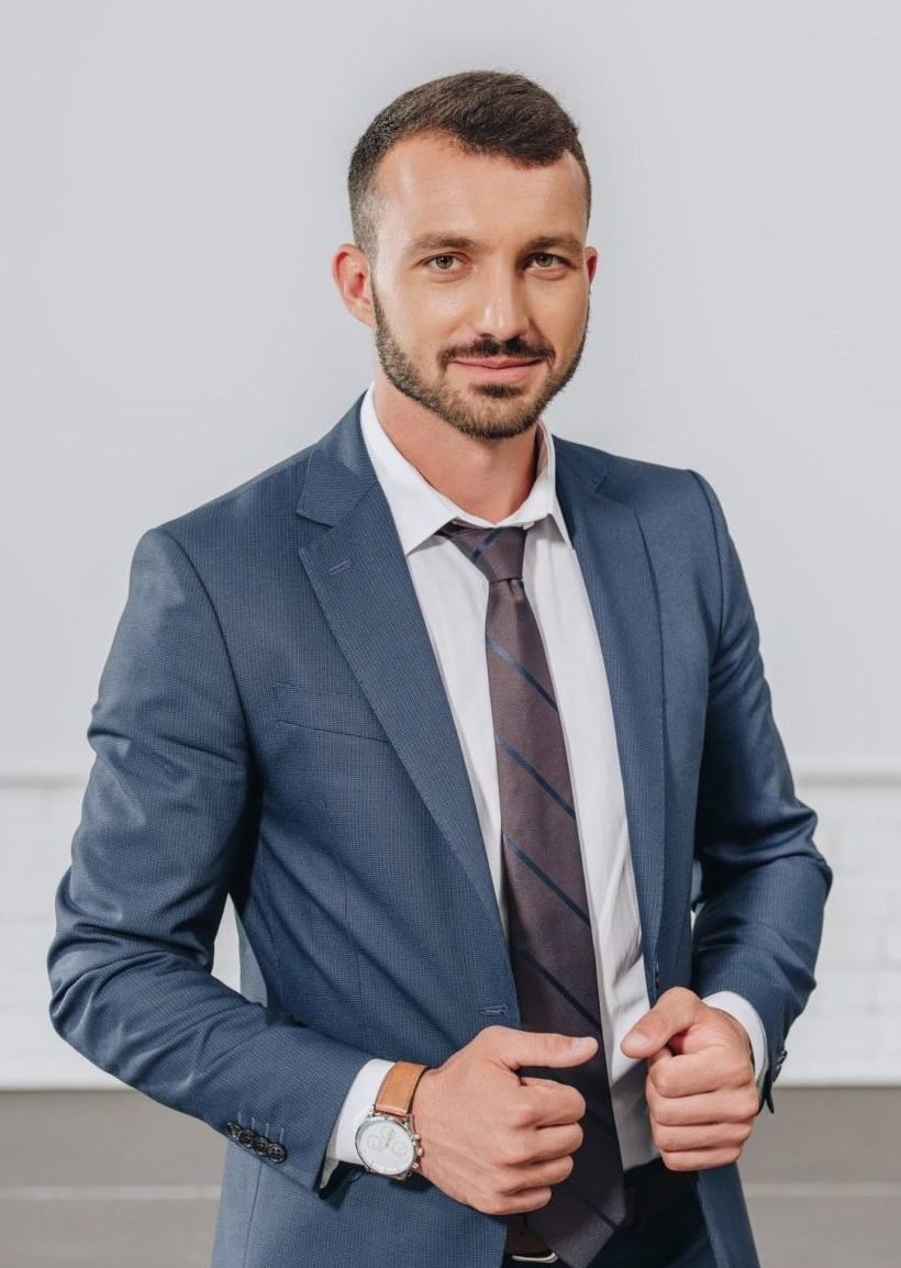 handsome businessman touching jacket and looking at camera in hub e1645410658679